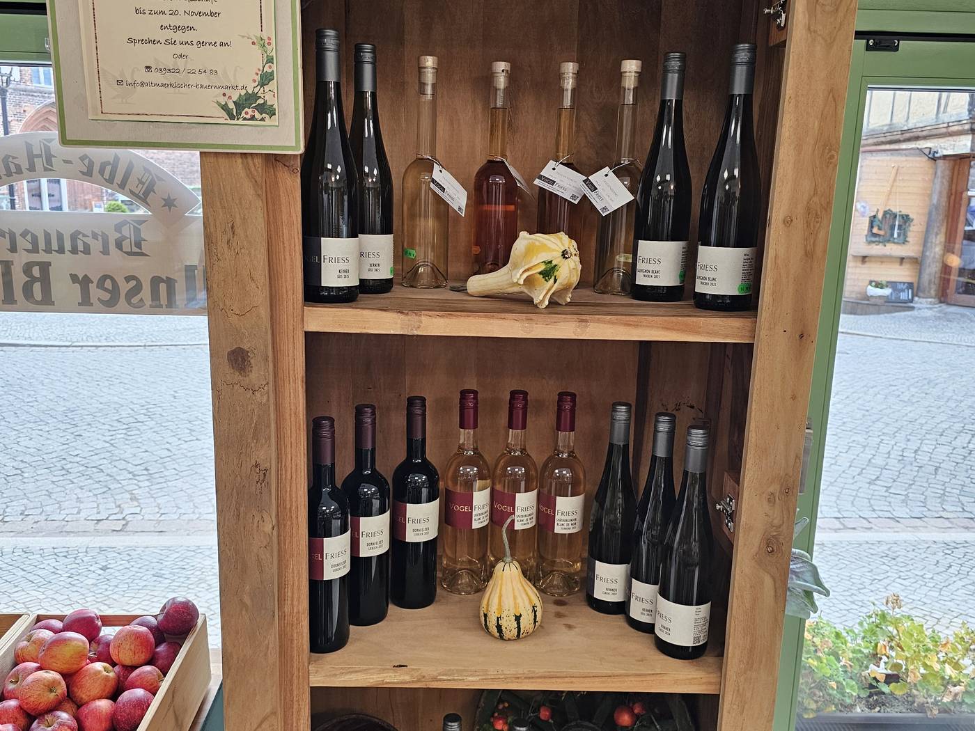Ein Holzregal am Fenster mit Rotwein, Roséwein und Weißwein.