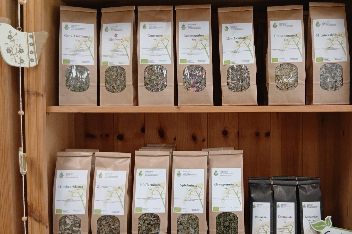 Papiertüten mit Kräutertees in zwei Reihen in einem Holzregal.